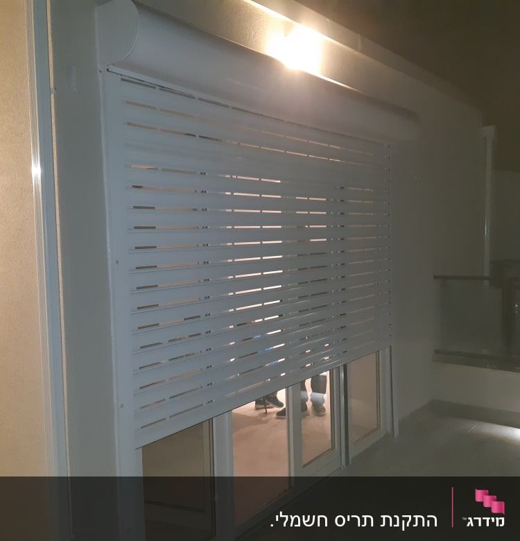 תריס אלומיניום לבן מותקן על חלון זכוכית